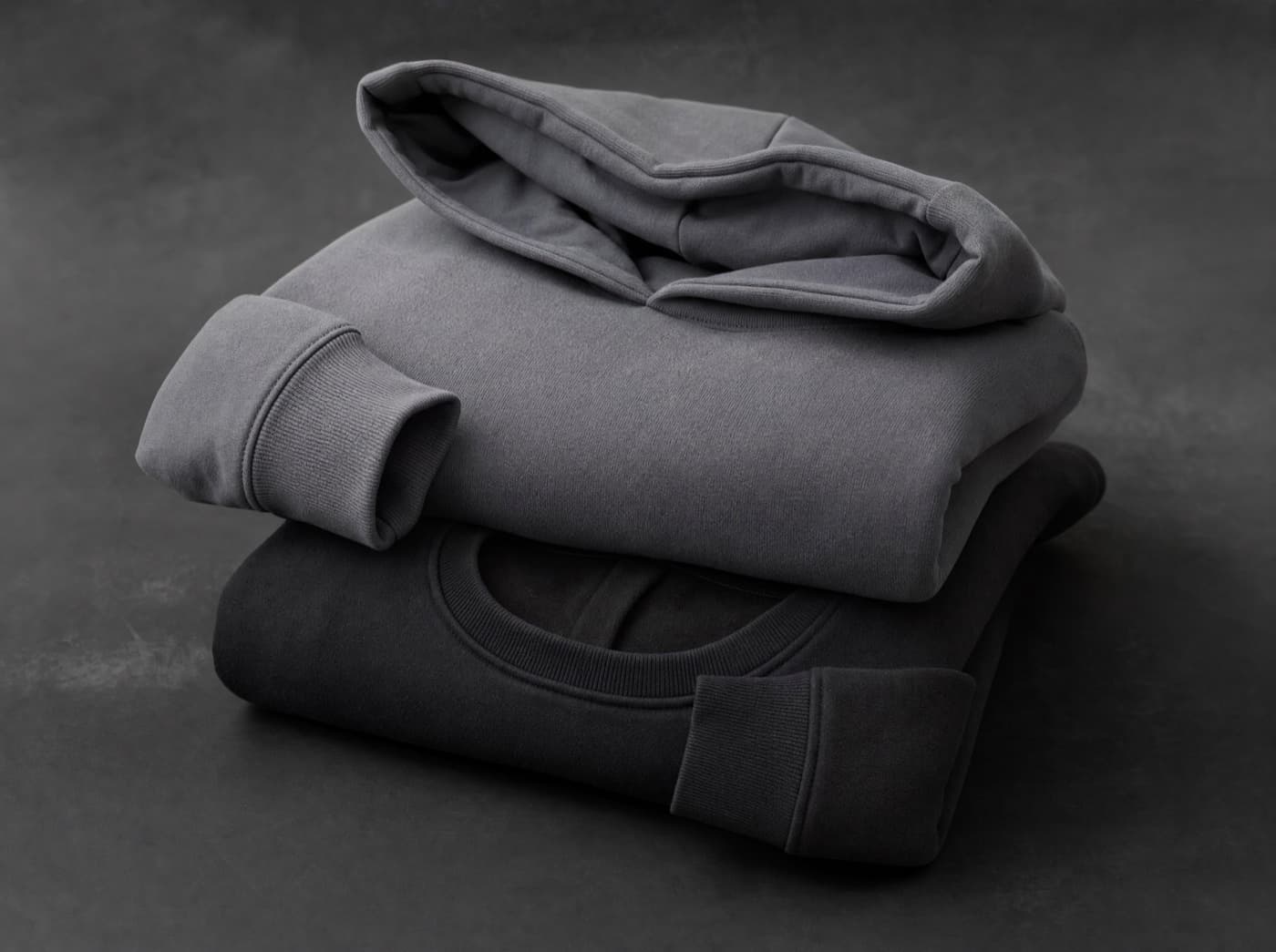KI-generiertes Bild: gefalteter Hoodie und Crewneck in Grautönen